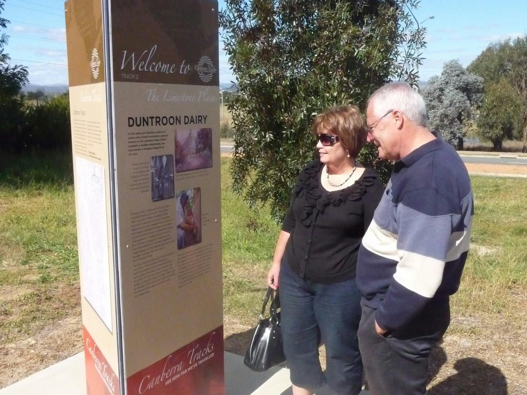 Man and Woman outdoors looking at tall sign