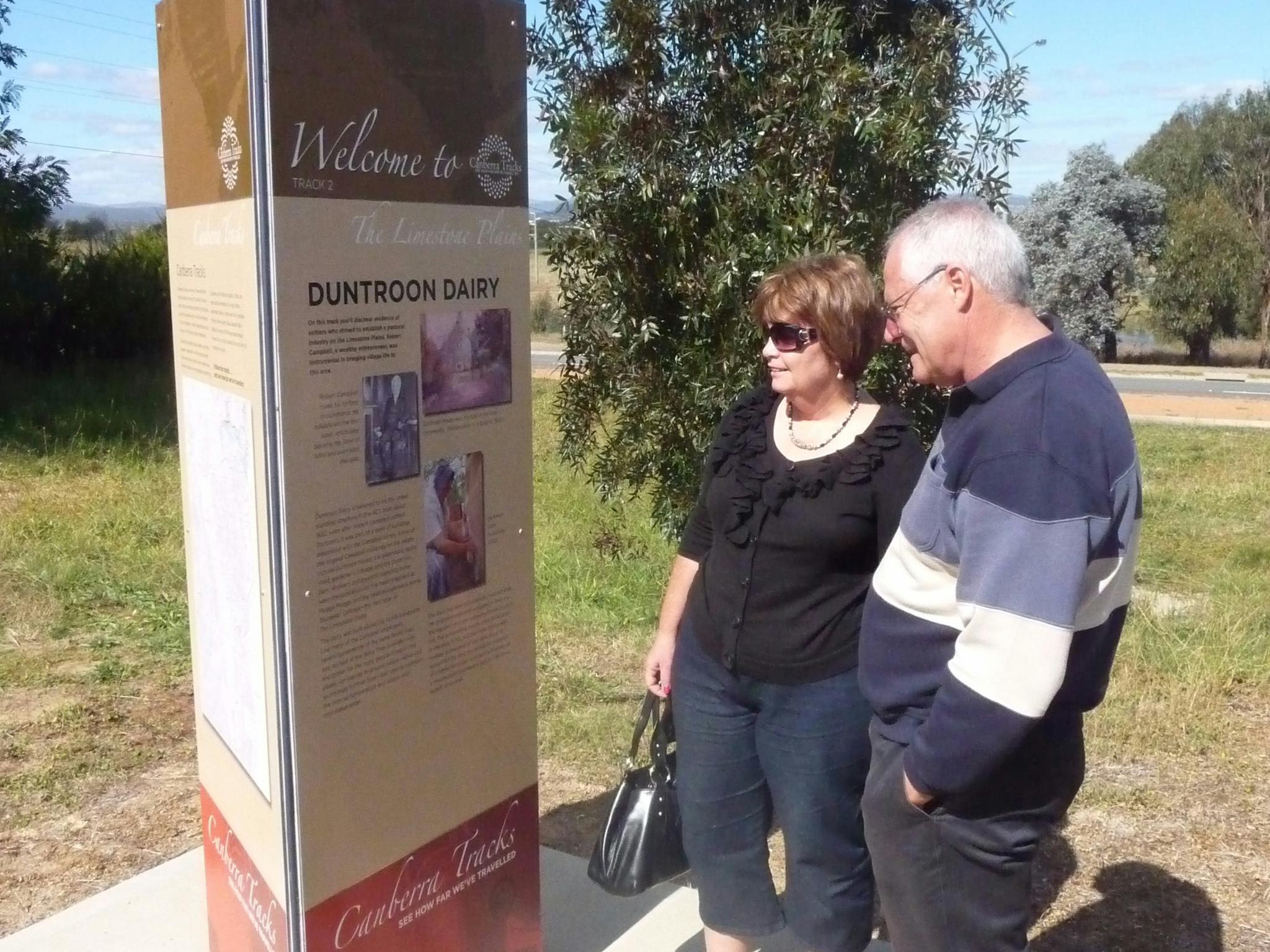 Man and Woman outdoors looking at tall sign