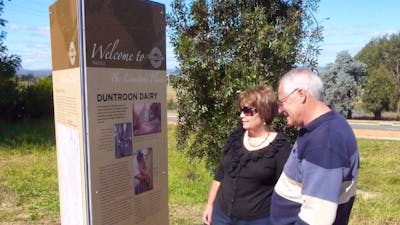 Man and Woman outdoors looking at tall sign