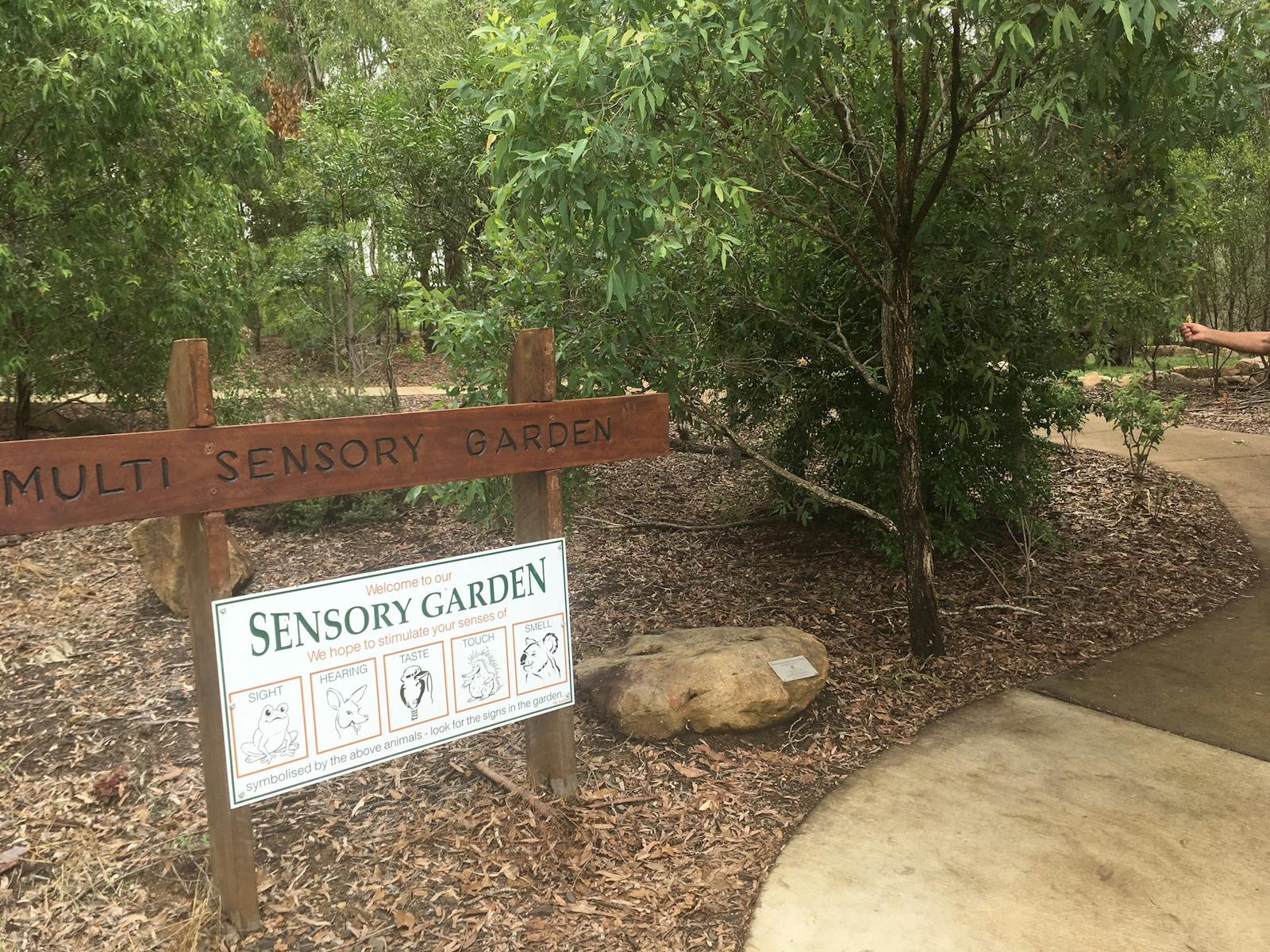Park reserve with a sign indicating a sensory garden area Park reserve with a sign indicating a sensory garden area