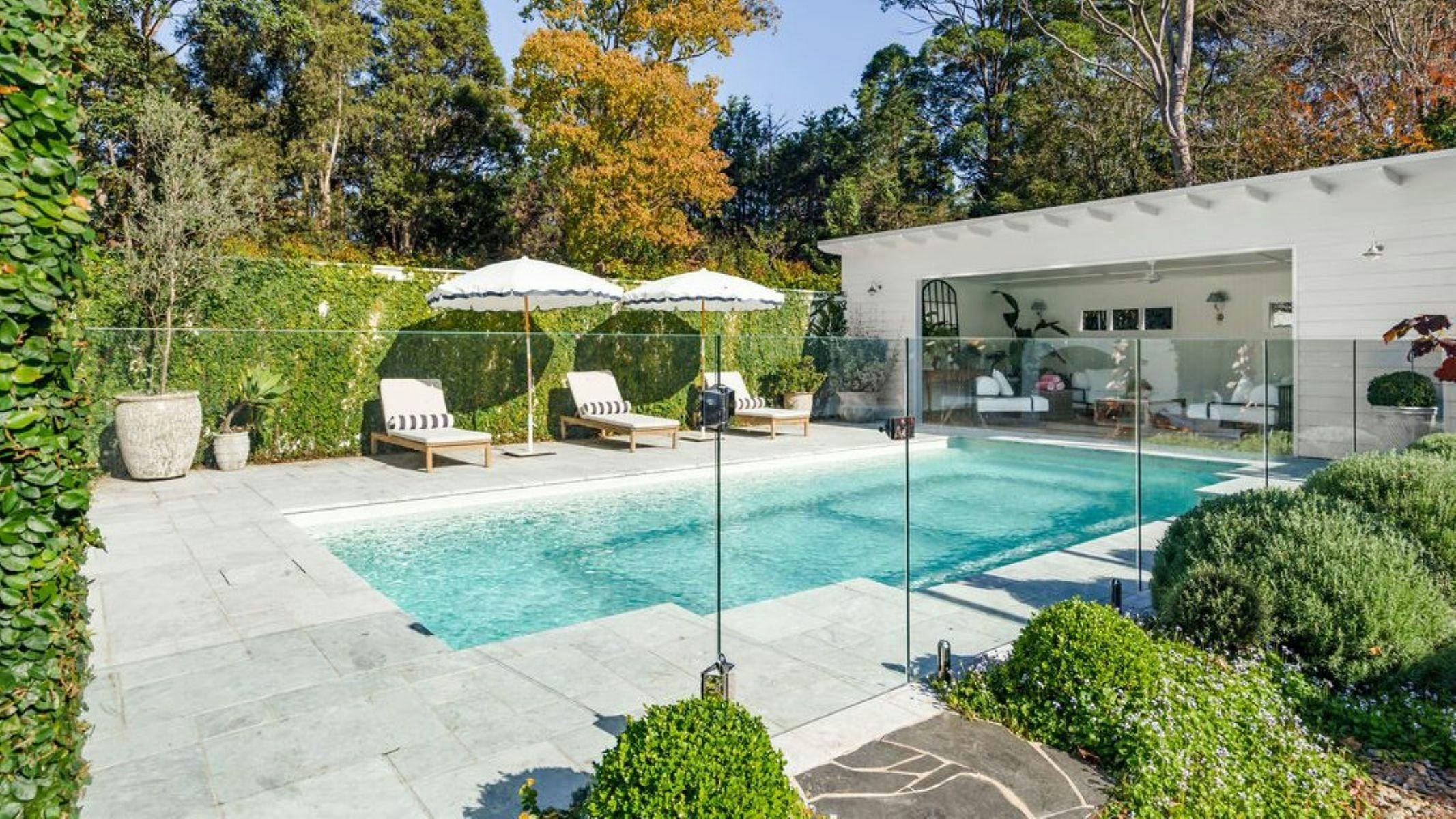 Image of pool area and alfresco dining area. Sun is shining and pool deck chairs are out.