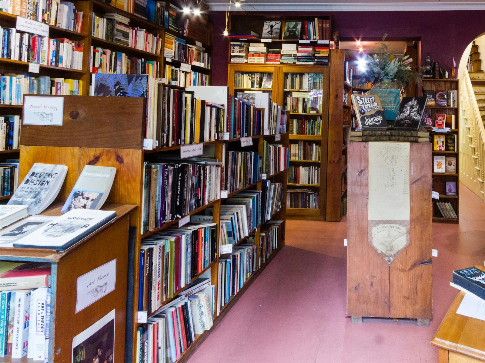 A view inside the bookstore with maroon walls covered in dark brown bookshelves, filled with books.