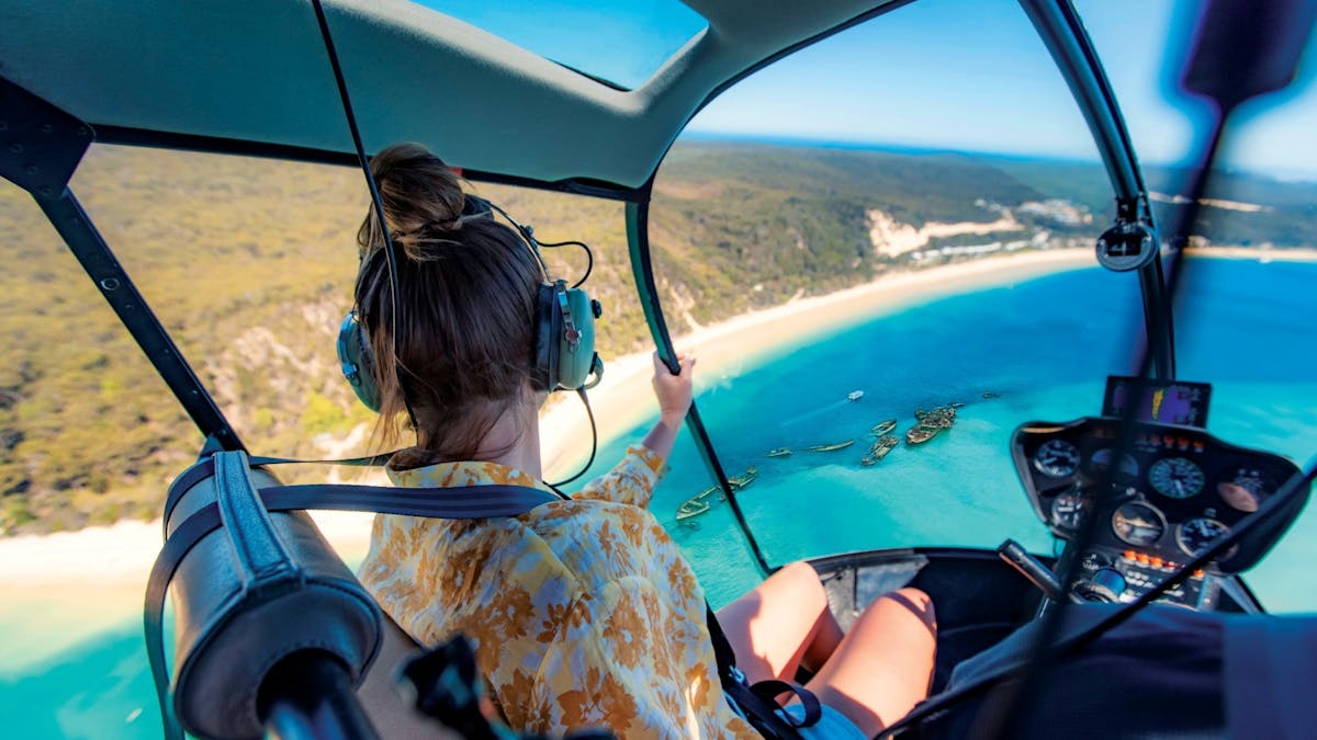 Women in a helicopter looking out over the view of the Tangalooma Wrecks and turquoise water