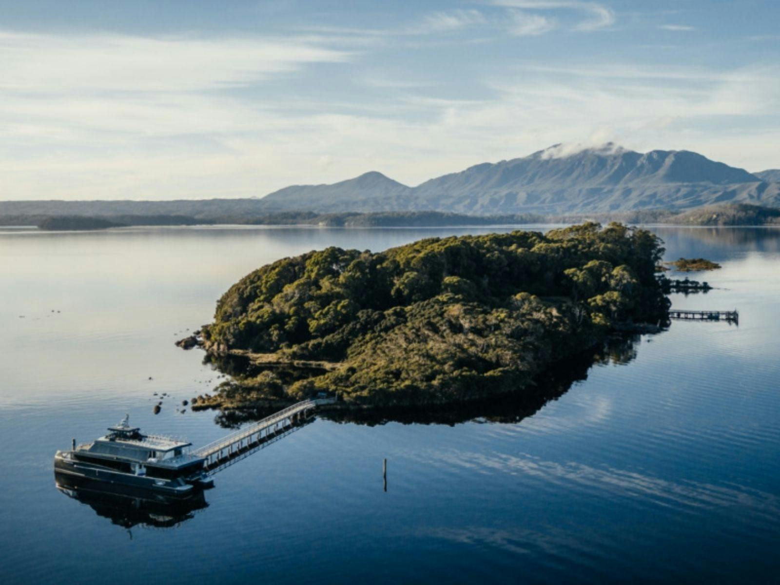 Large catamaran moored at a getty on an island in the middle of a remote river with very calm water