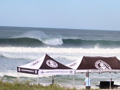 Big waves breaking in oceacn with a jones beach boardriders gazebo up on the beach in foreground