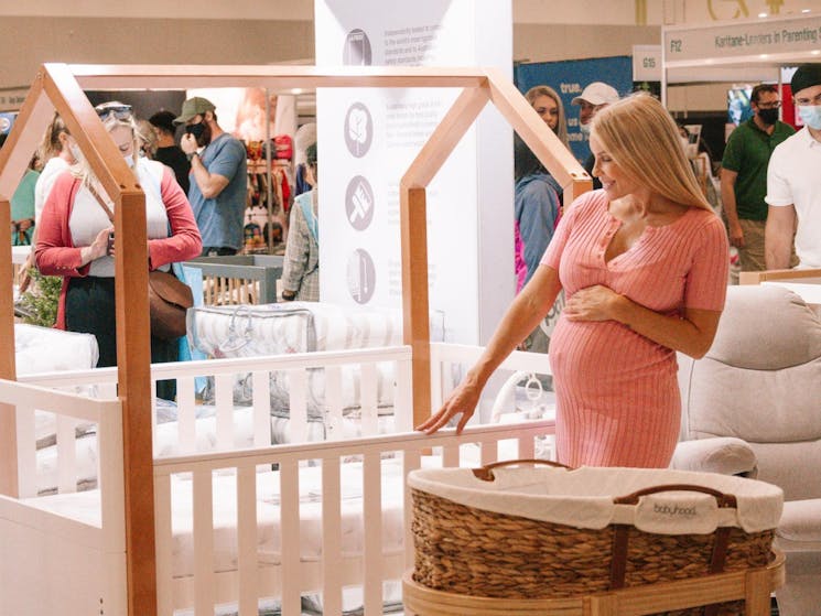 pregnant woman looking at cot