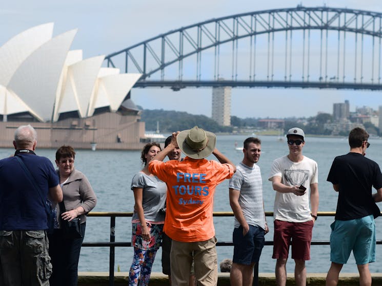 Sydney Sightseeing bus tour group is taking pictures with the Sydney Opera House in the background