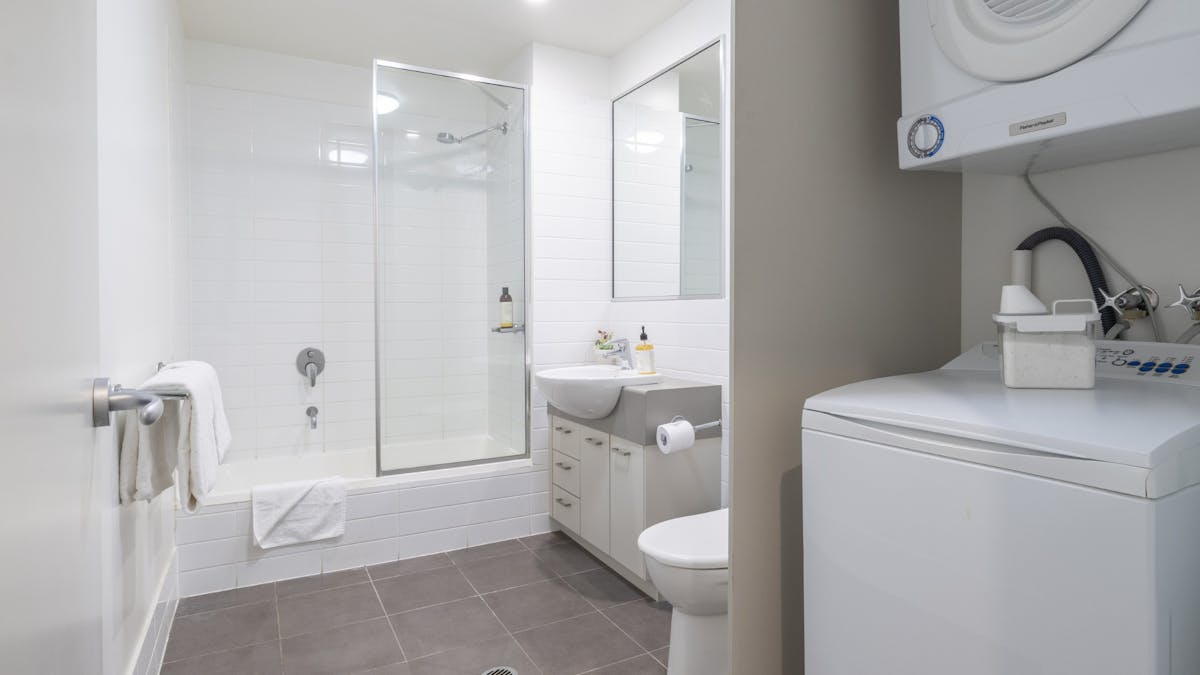 Washing machine and dryer in a bathroom with bath, vanity, and toilet.