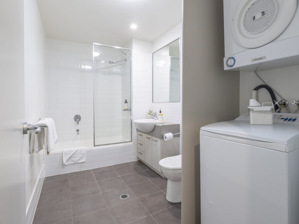 Washing machine and dryer in a bathroom with bath, vanity, and toilet.