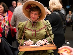 Poet in nineteenth century dress and bonnet with portable writign table