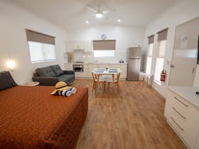 view of Studio Cabin interior - open plan with queen bed, full kitchen, dining table, couch and TV