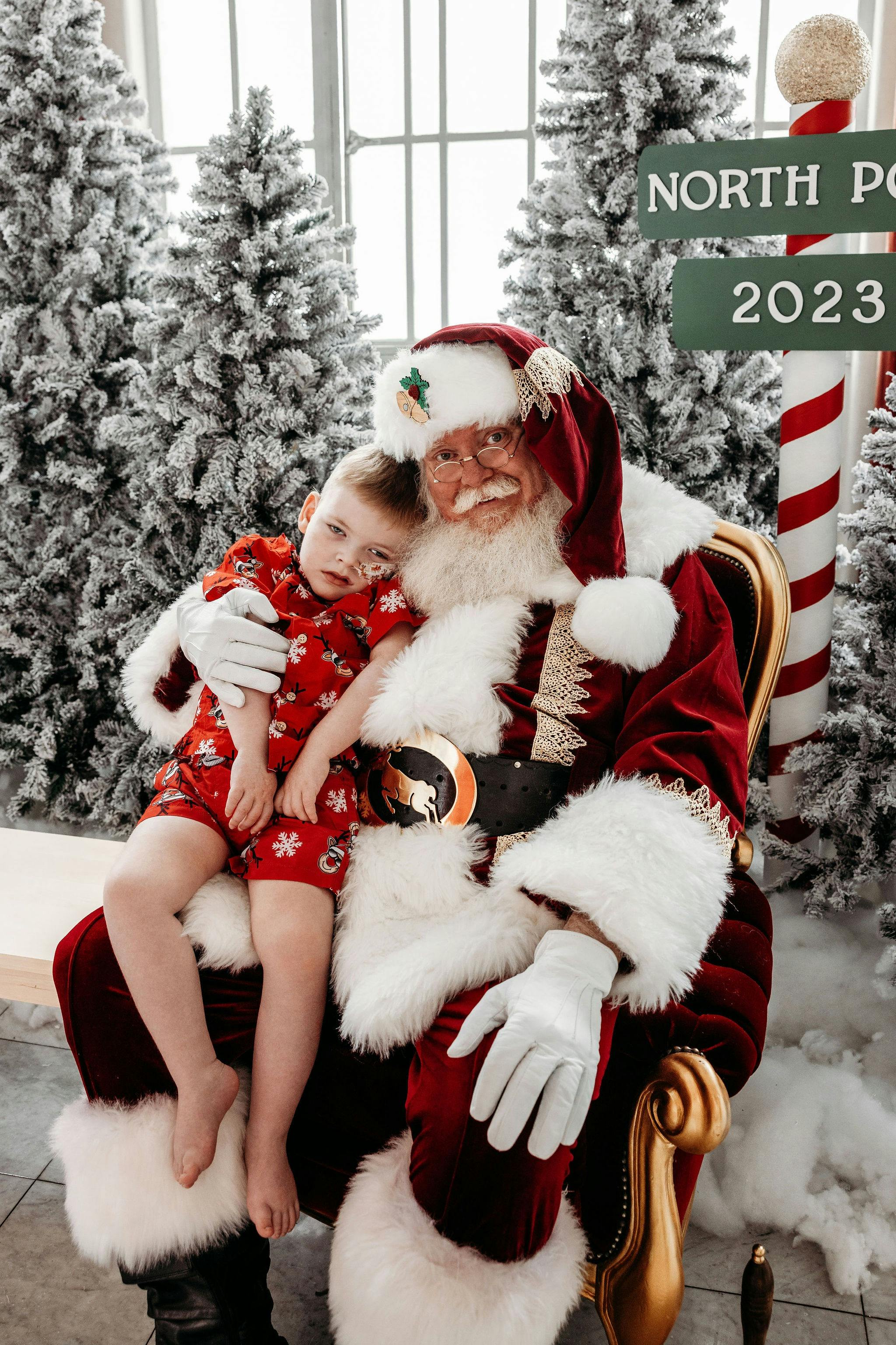 Santa with a child sitting on his lap. A family sitting with santa.
