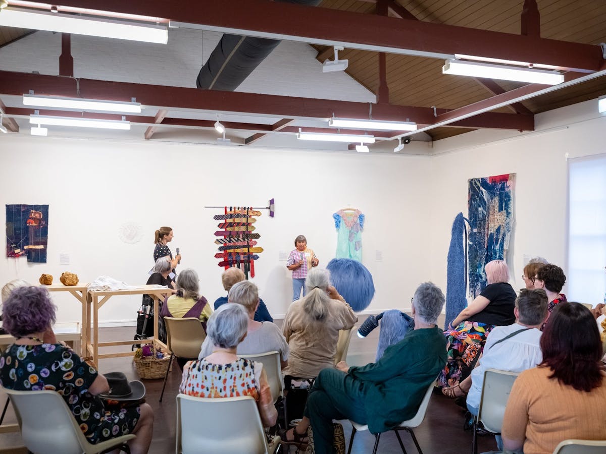 People sitting while listening to an artist speak about their art
