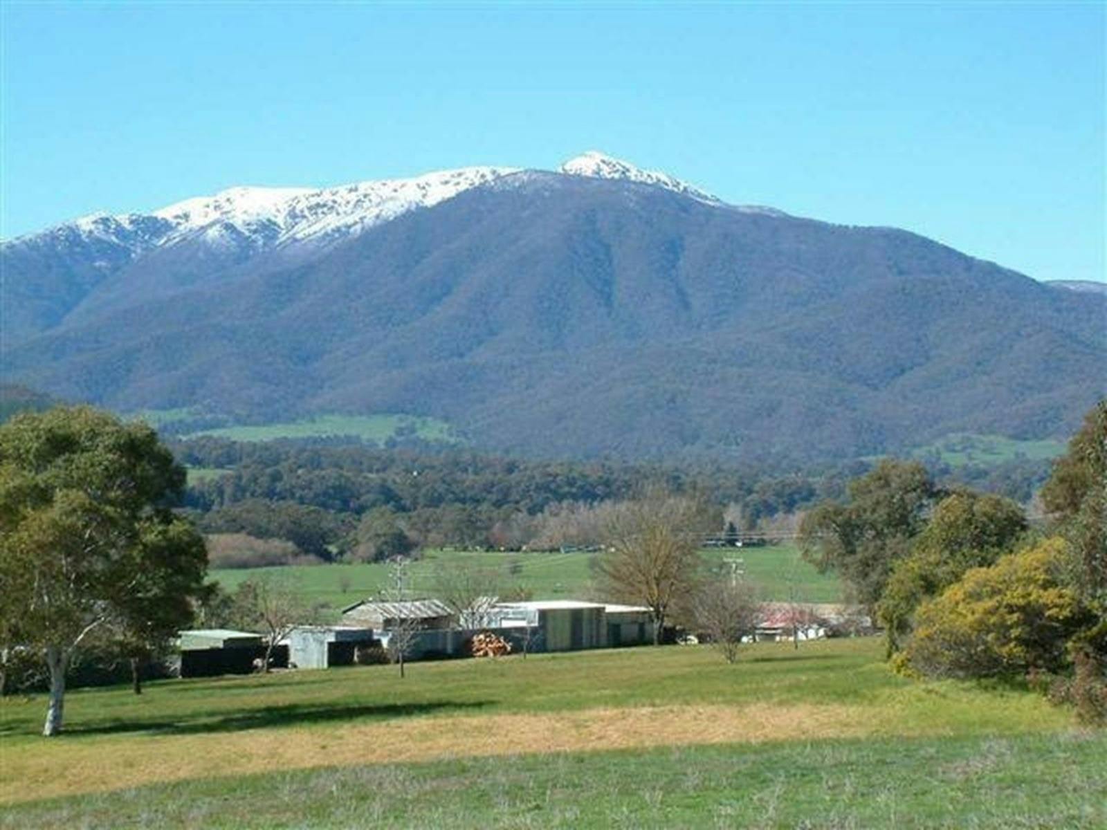A mountain behind houses with snow on the top