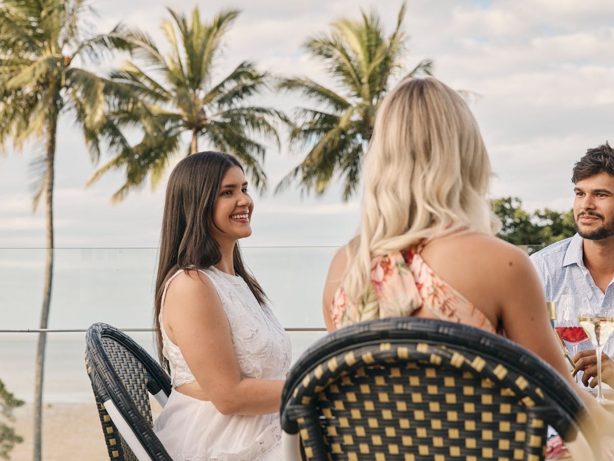 People sitting at table with palm trees in background