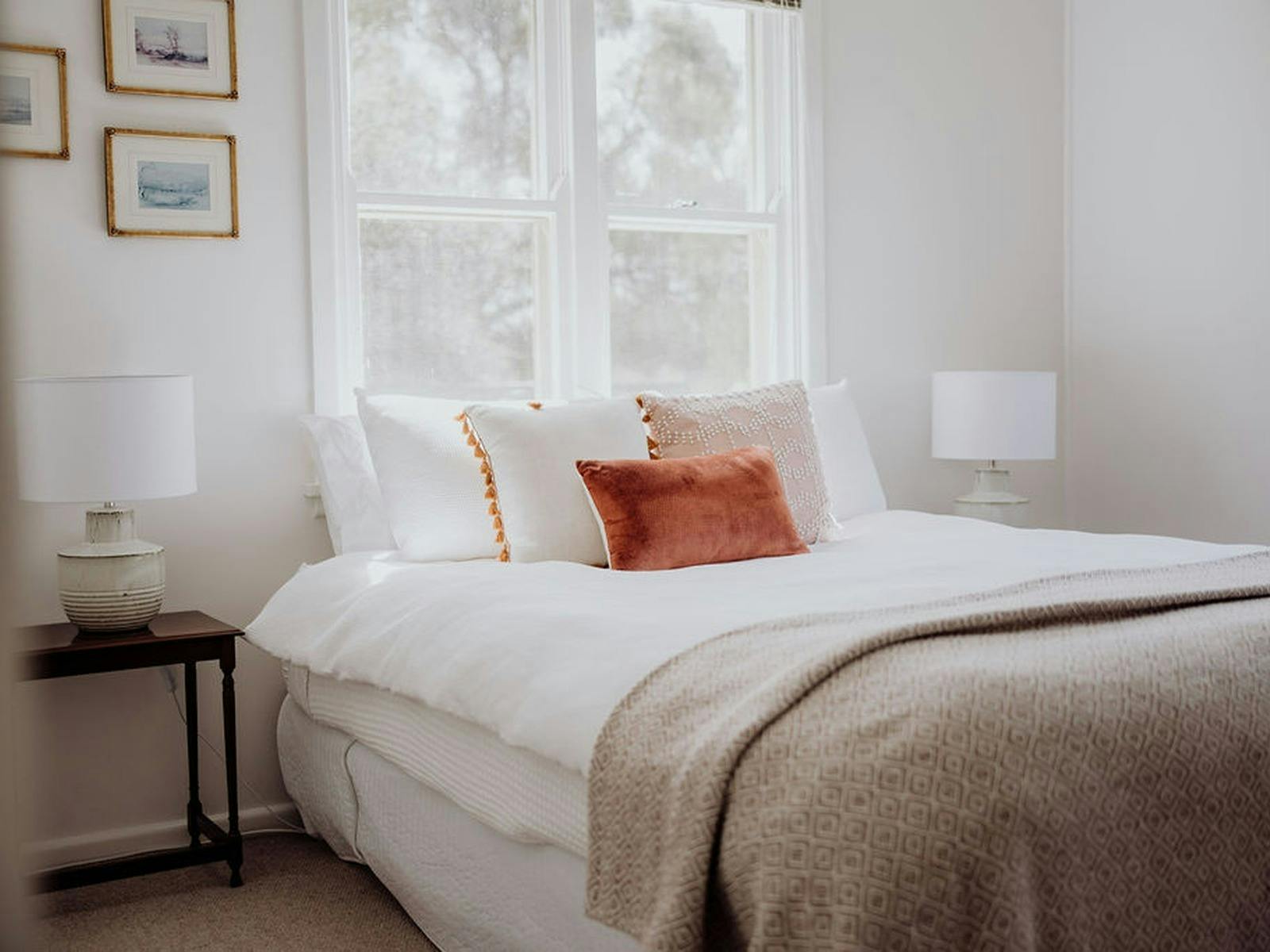 Light-filled bedroom a queen bed, soft neutral furnishings and peaceful country-style decor
