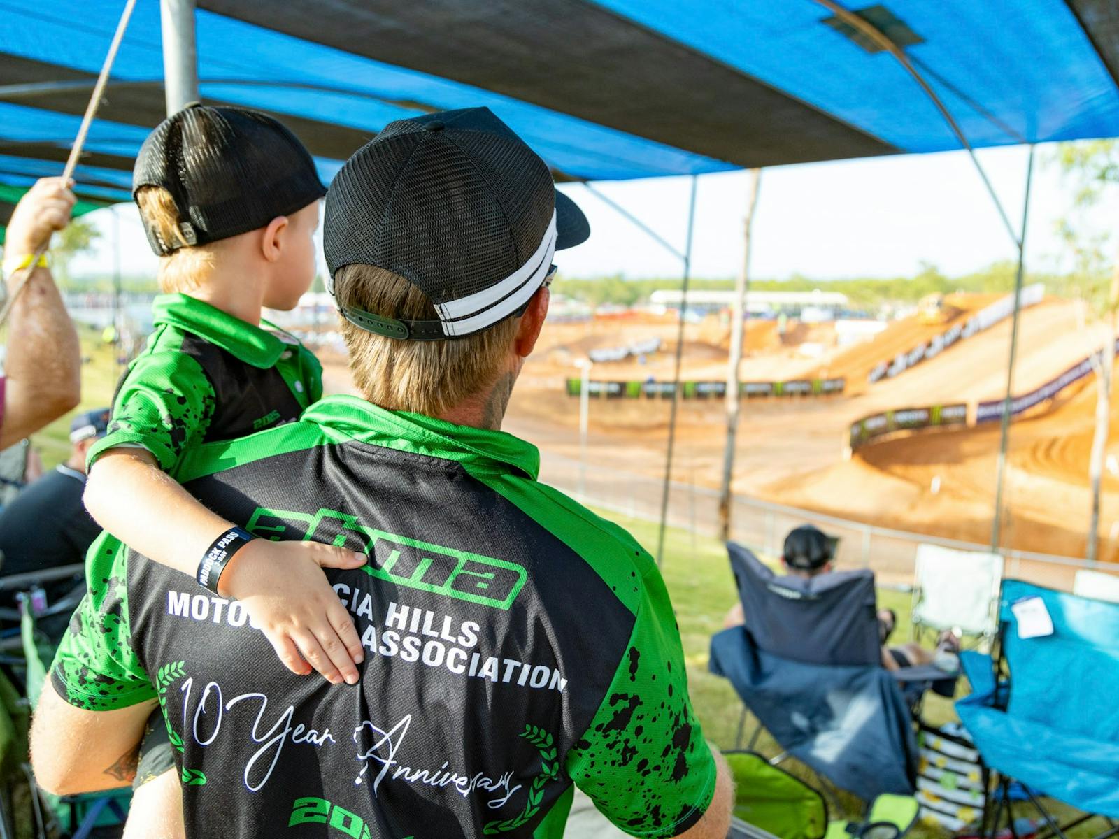 Man holding a child looking out at the MXGP track