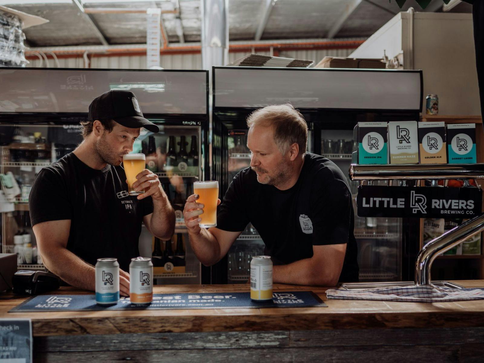 Two men behind a bar tasting beer at Little Rivers Brewing Co.