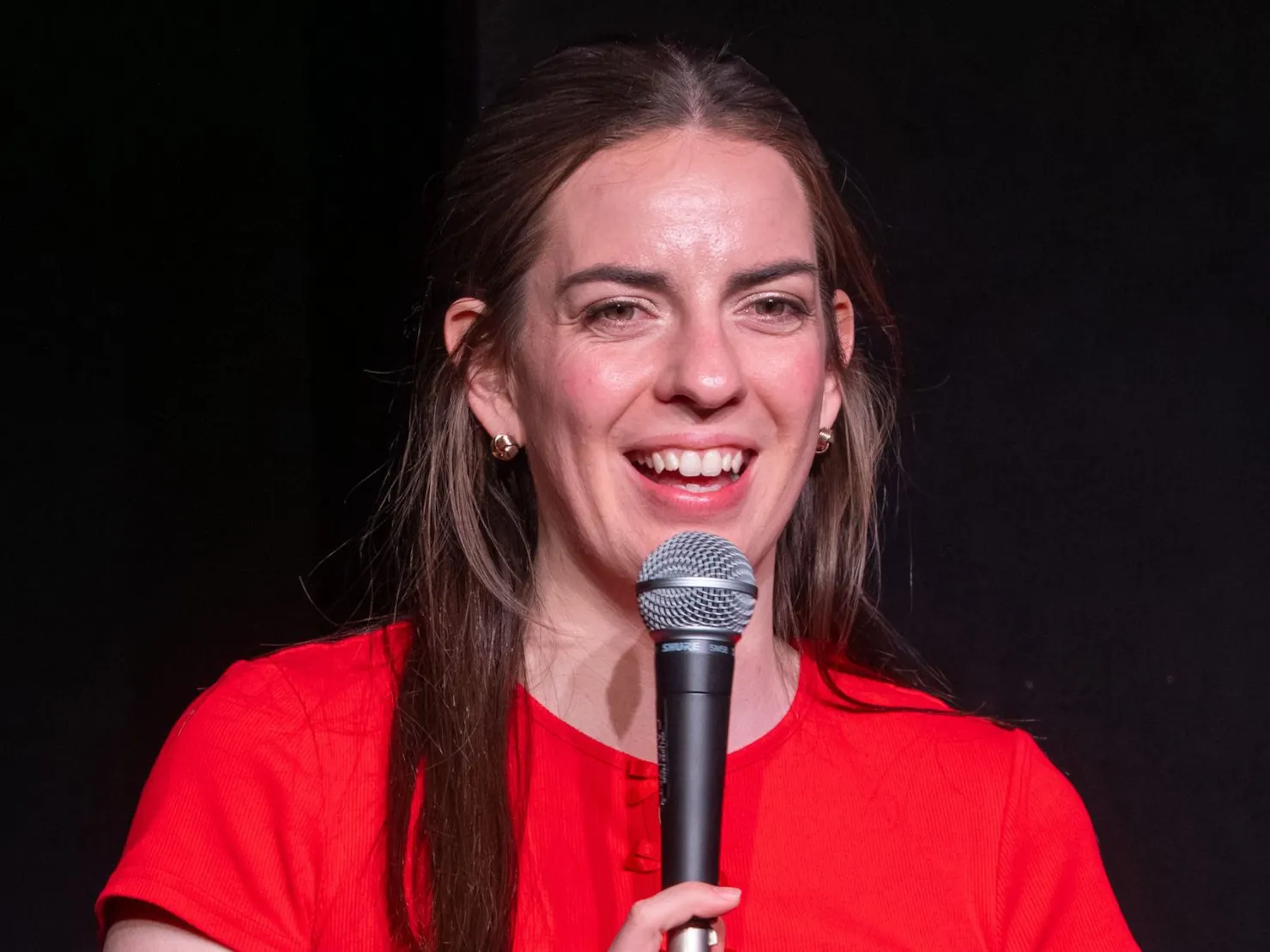 A girl in red shirt holding a microphone.
