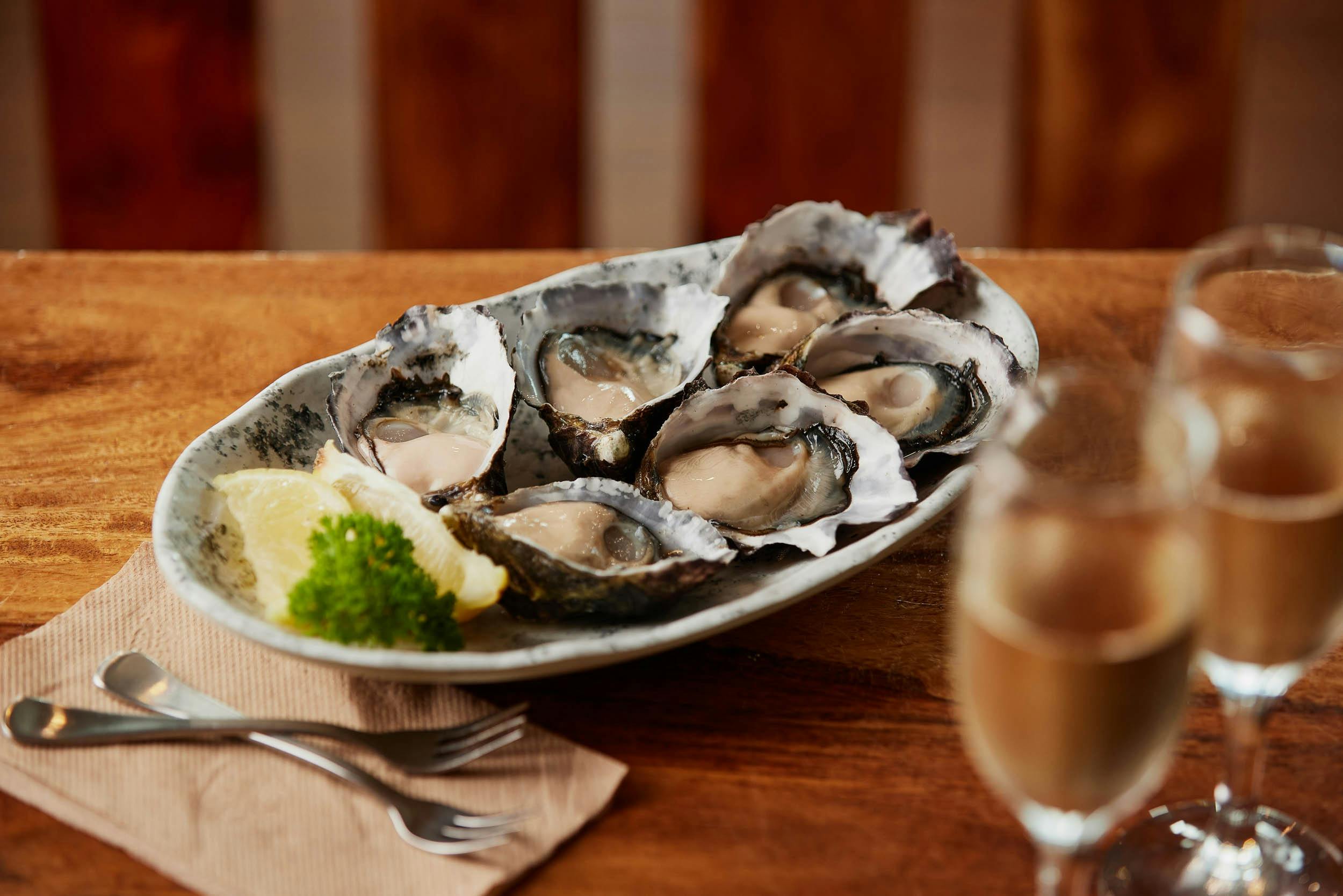 A plate with half a dozen freshly split oysters and lemon
