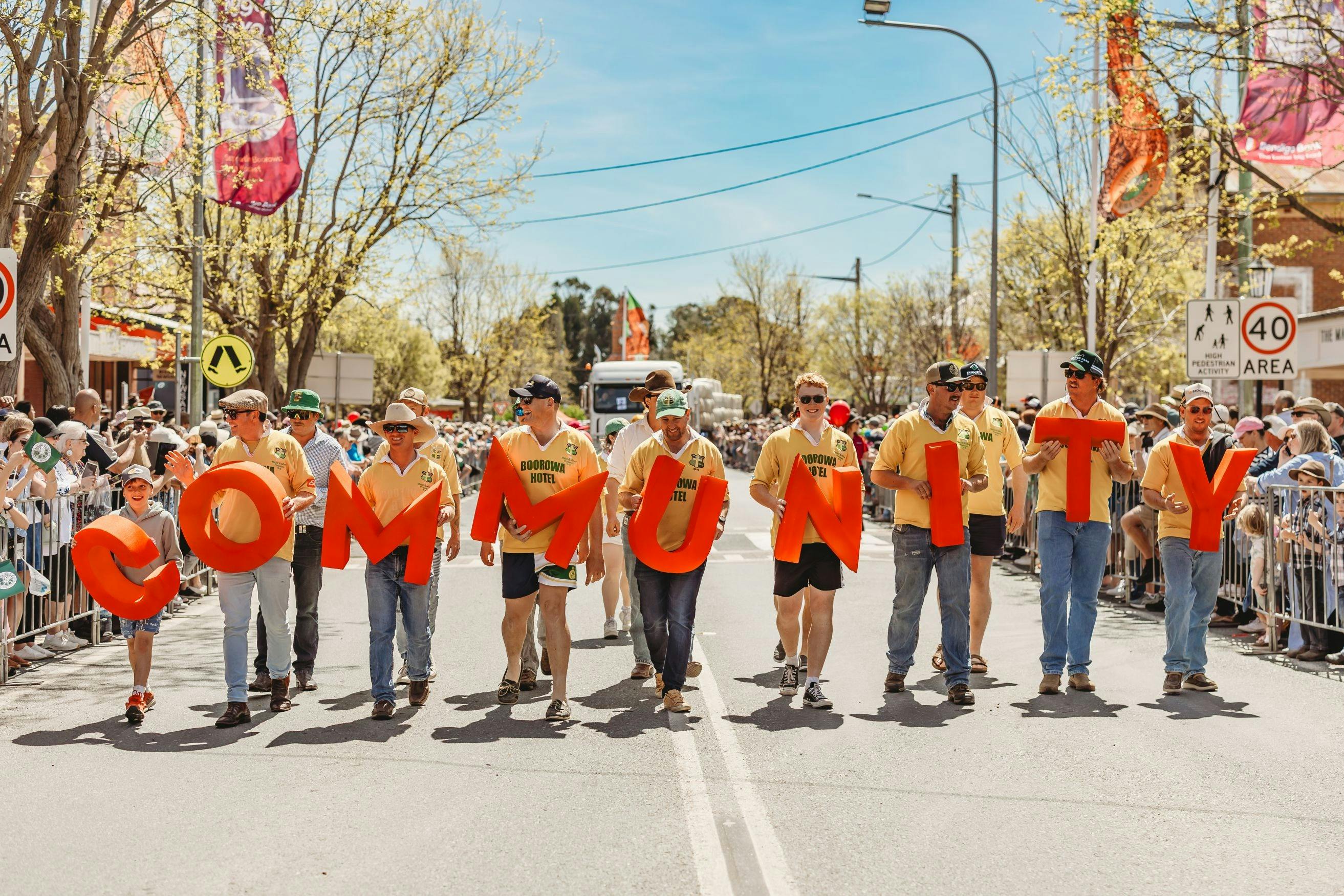 Street parade with a line of people holding big letters in a row, spelling "COMMUNITY"