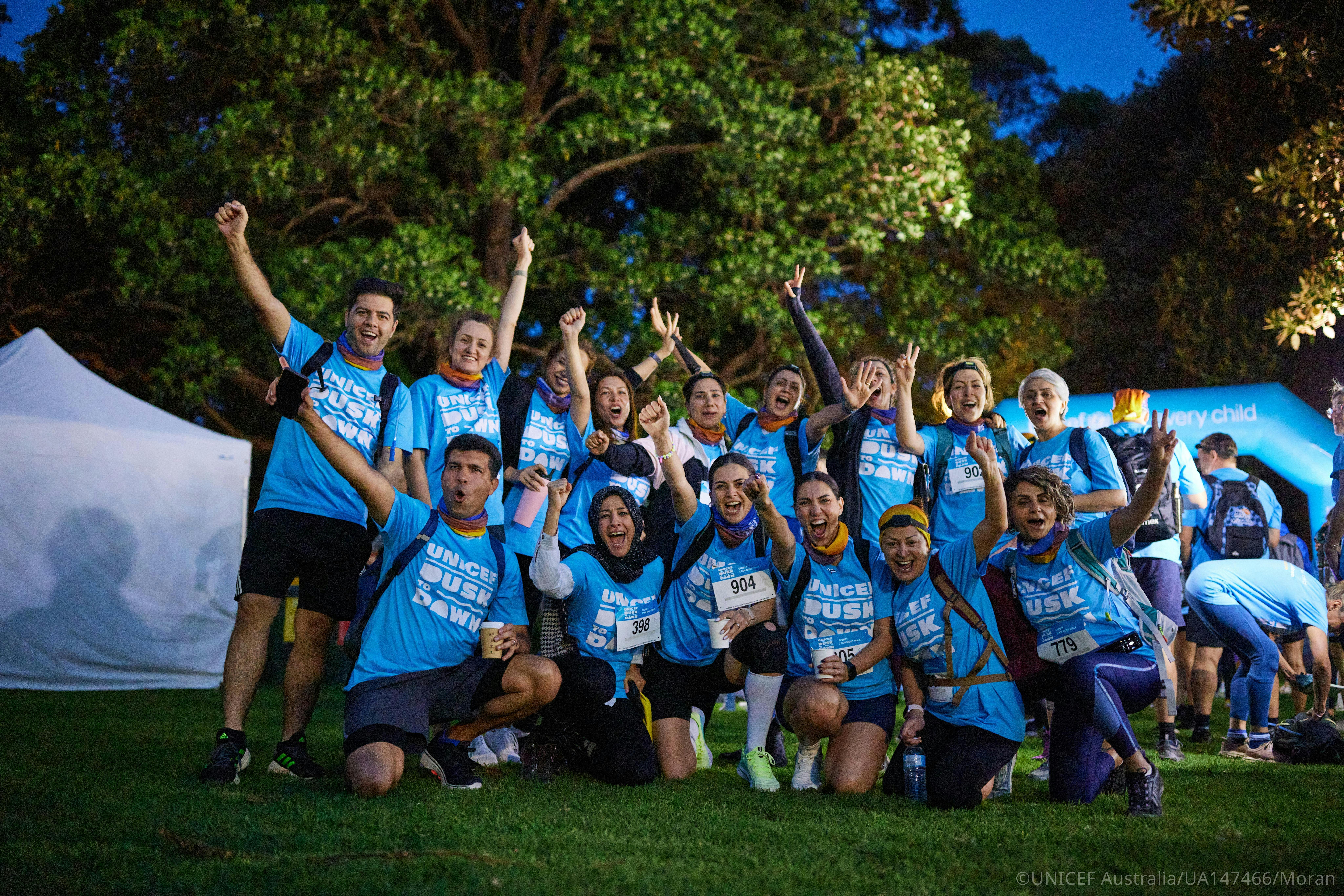 Large group of Dusk to Dawn participants posing together outdoors at night.