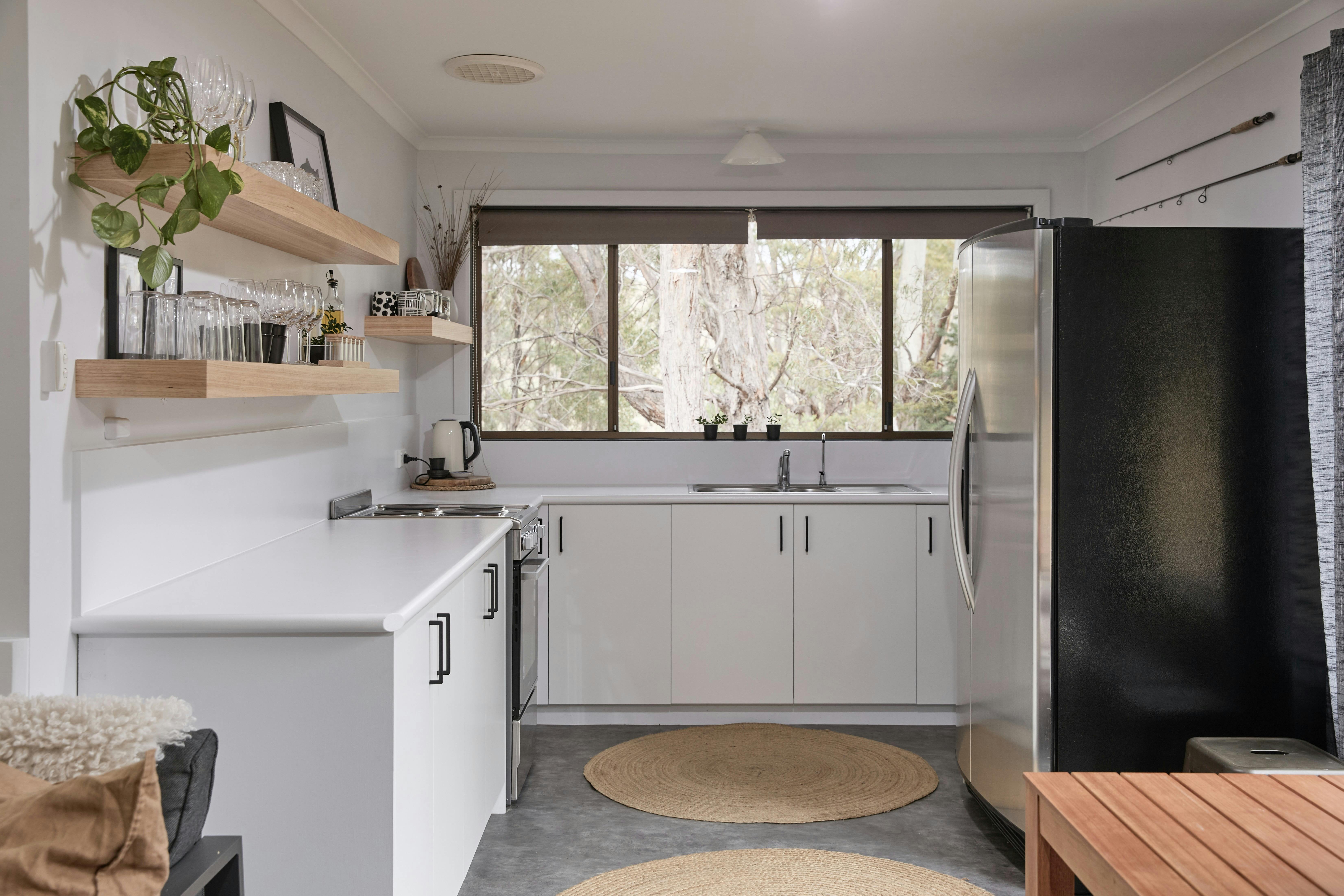 A bright kitchen with large window overlooking bush setting