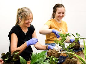 Two Ladies with indoor plants wrapping twine around the kokadama balls