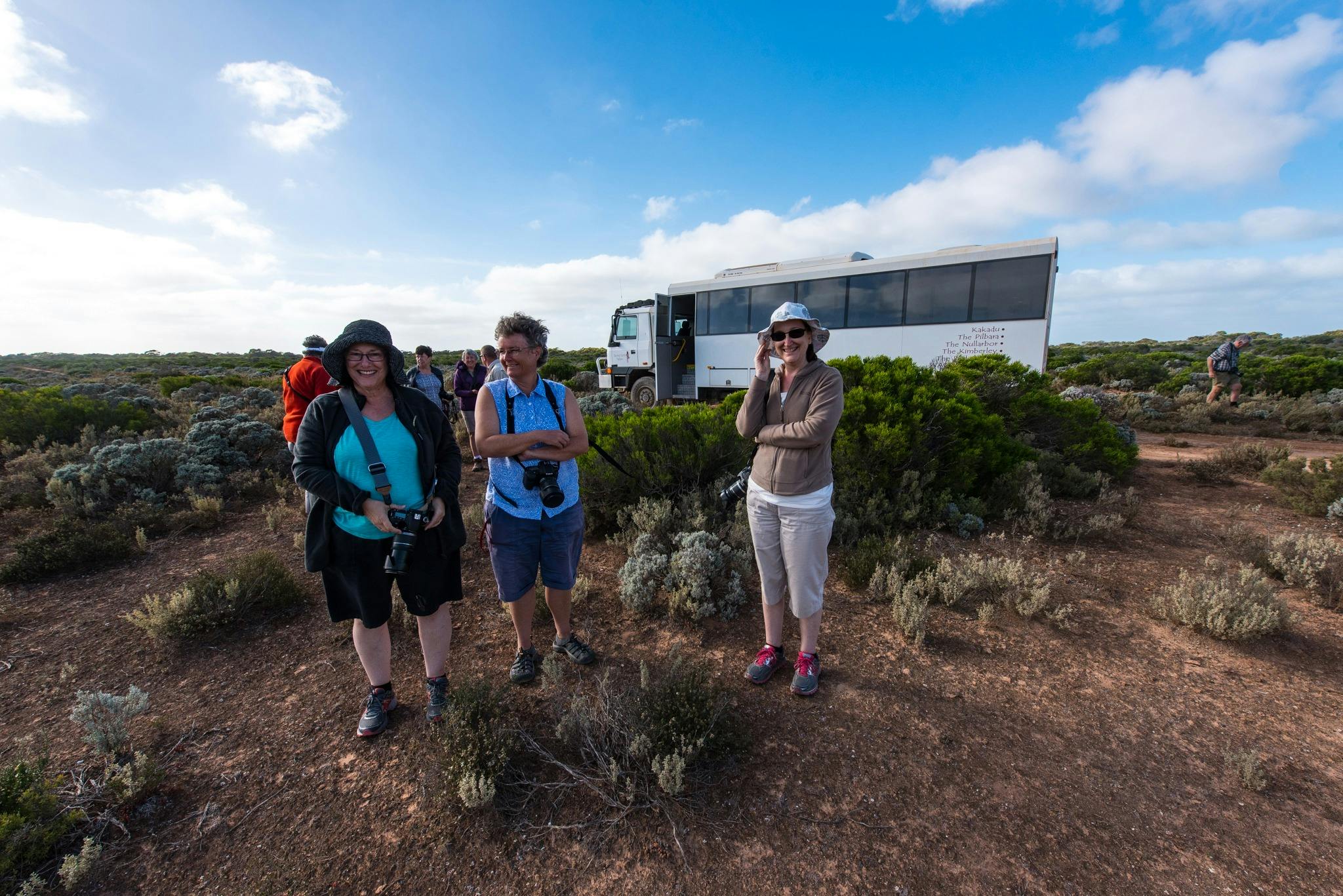 3 females standing in front of the coach, with their cameras