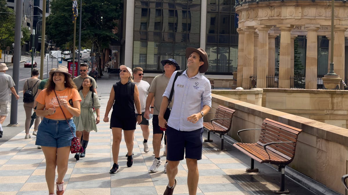 A tour group walks along a patterned stone pathway in a city center.