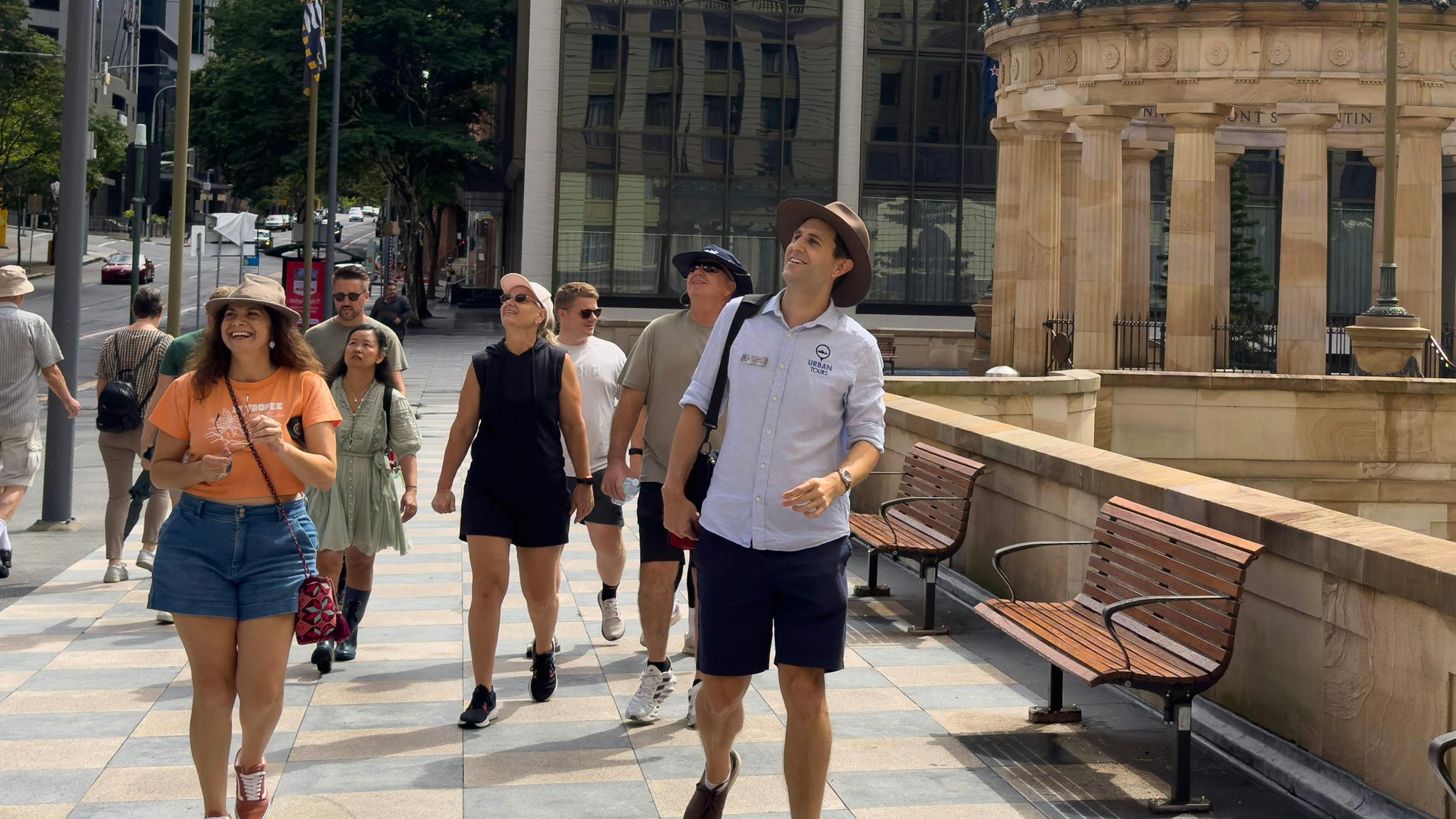 A tour group walks along a patterned stone pathway in a city center. A tour group walks along a patterned stone pathway in a city center.