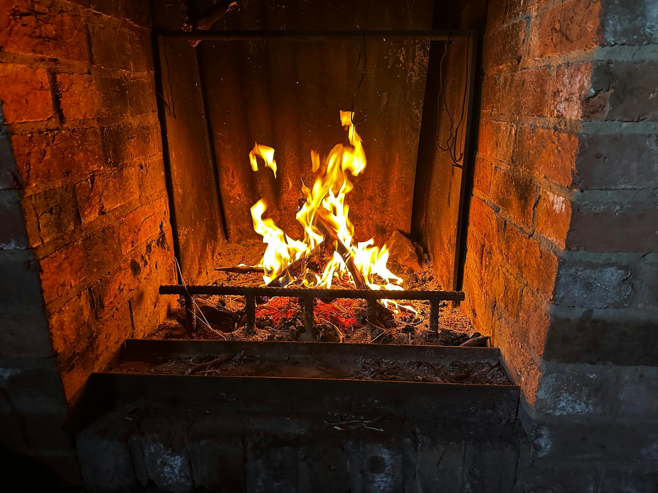 A campfire inside a shelter burning brightly.
