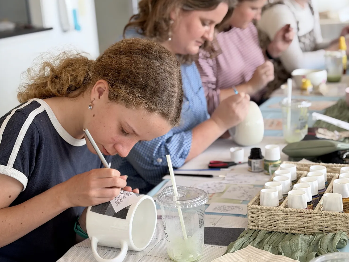 Guest hand-painting a ceramic cup at a NOA Matcha workshop