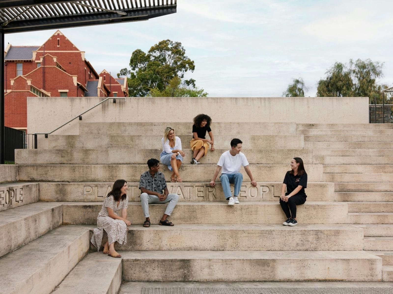 People sitting on steps and listening to the tour guide