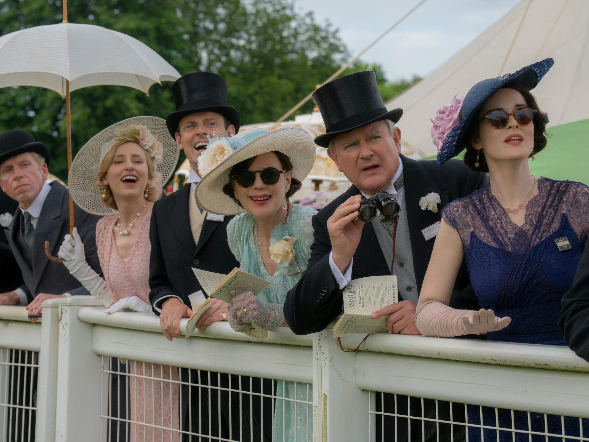 people leaning on fence wearing Downton Abbey era clothes