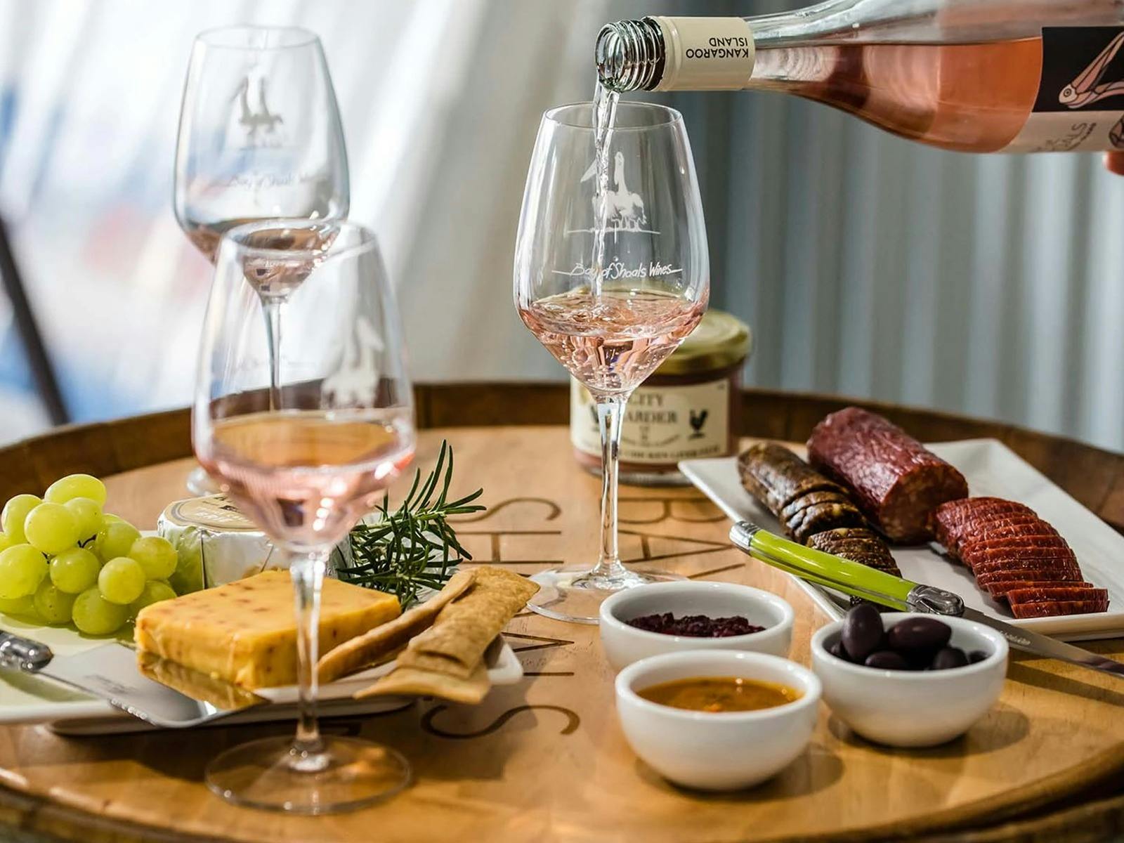 Wine is poured into a glass next to an array of snacks