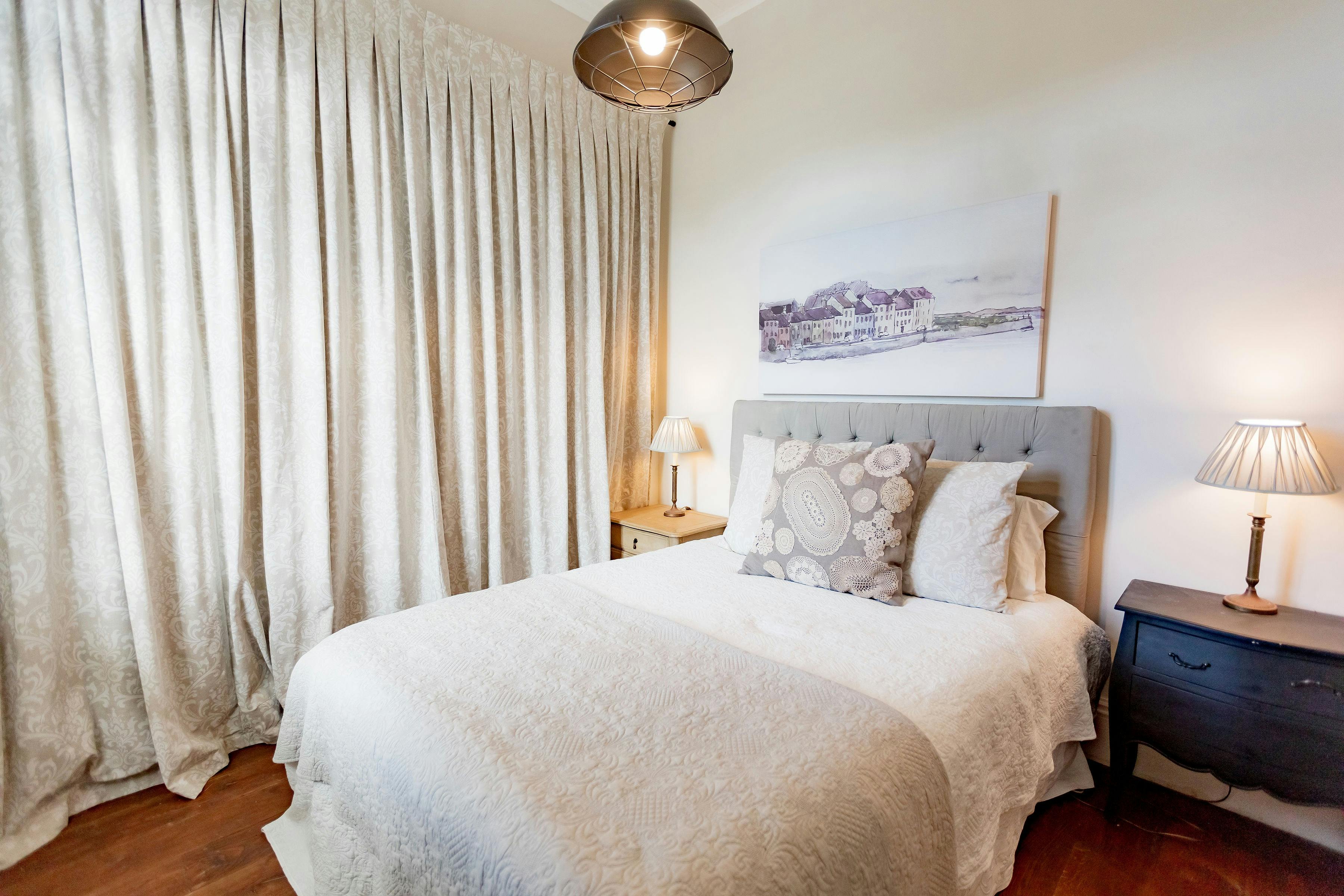 Bedroom with off white soft funrishings and dark floors