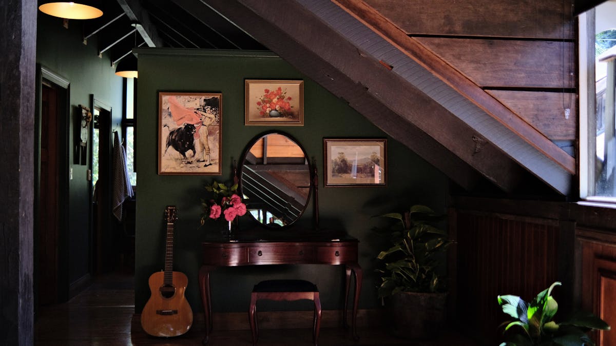 Vintage furnishings, guitar,and artwork with dark green wall.