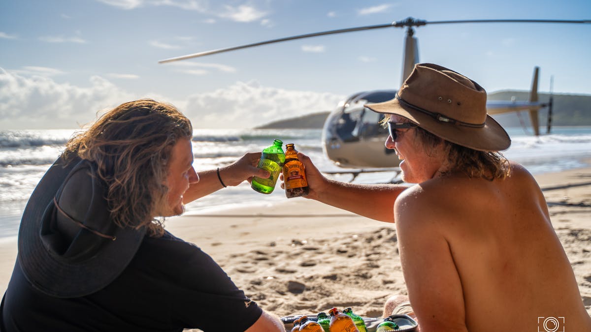 Two Mates enjoying a Brew on a remote beach with the RaptAir  Helicopter on the high water mark