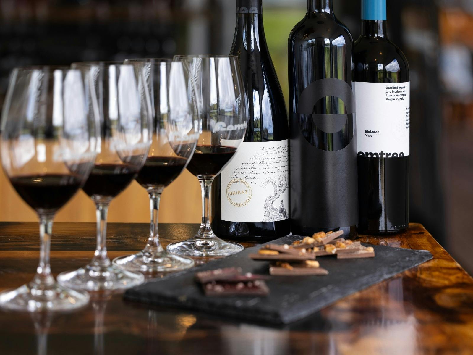 wine glasses filled with red wine alongside shards of chocolate.