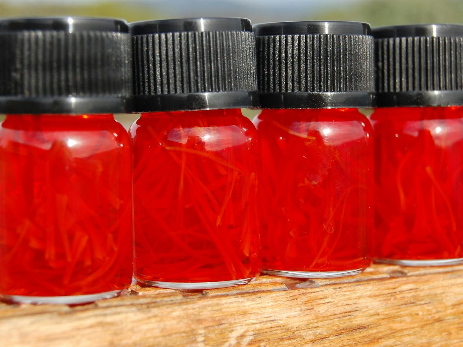 Four bottles of saffron infused in water for 24 hours showing bright red colour