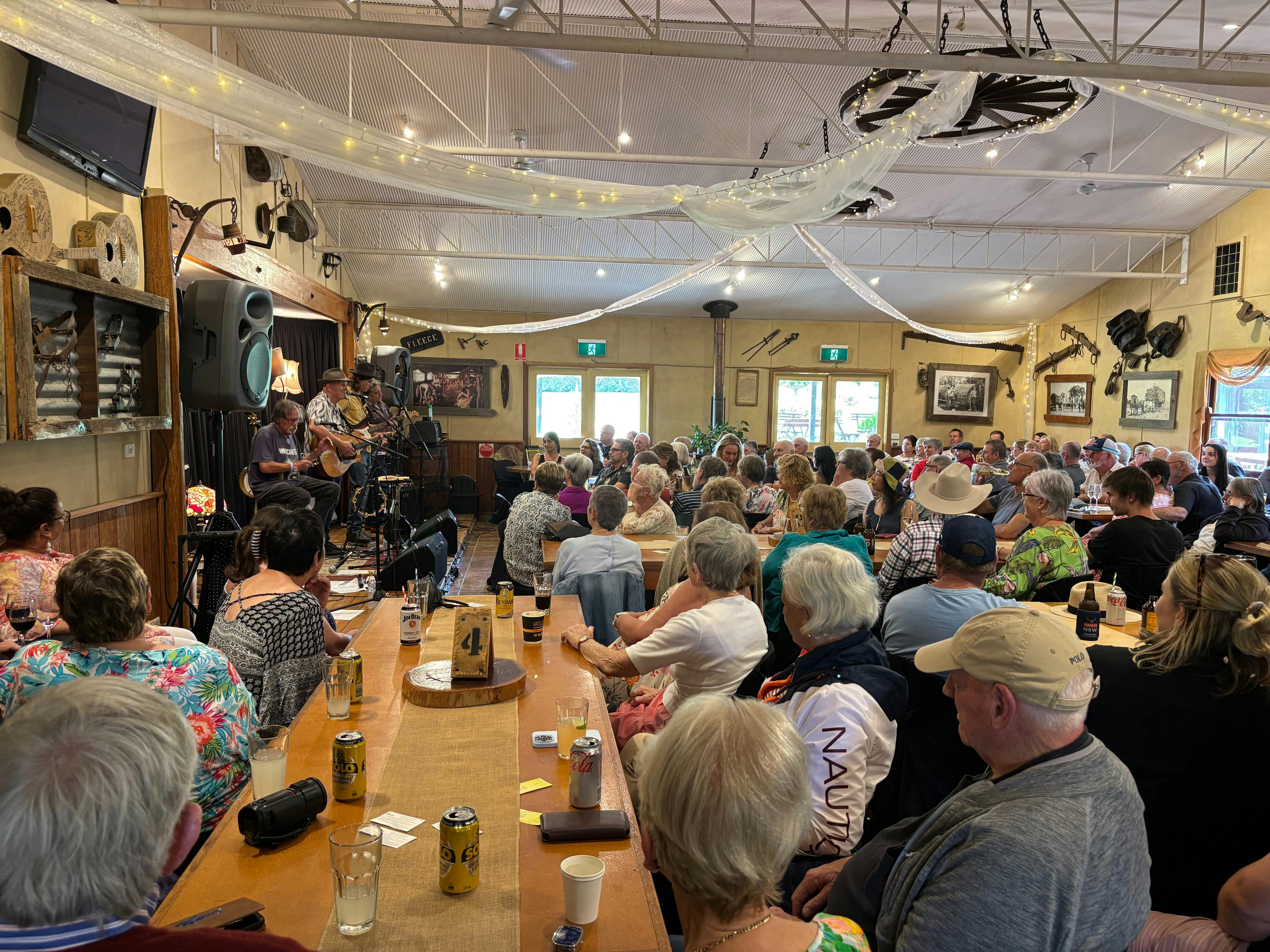 A room full of people sitting at tables watching musicians perform on stage.