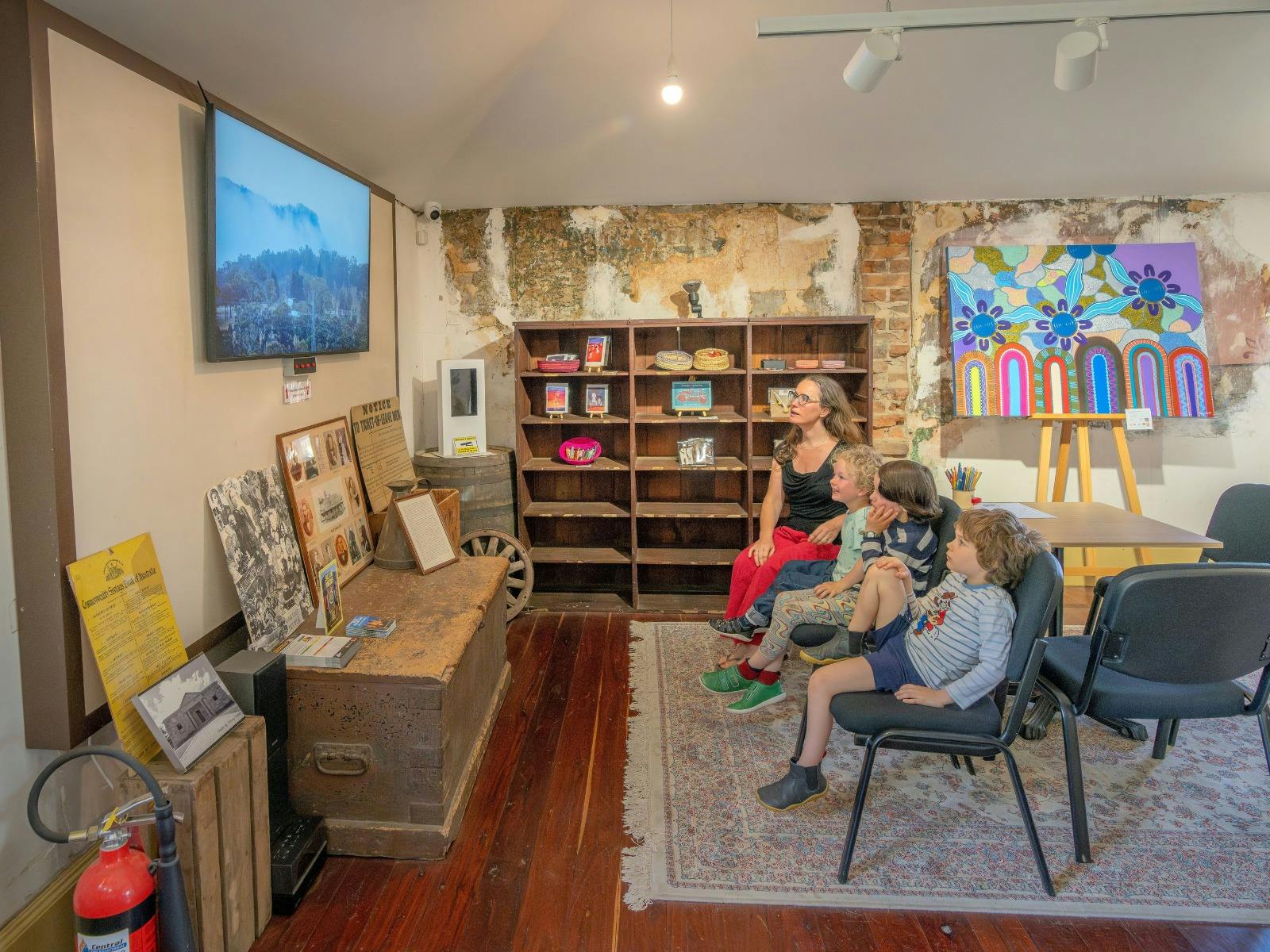 A family watches a short film about Hartley inside the Kew Y Ahn Aboriginal Gallery
