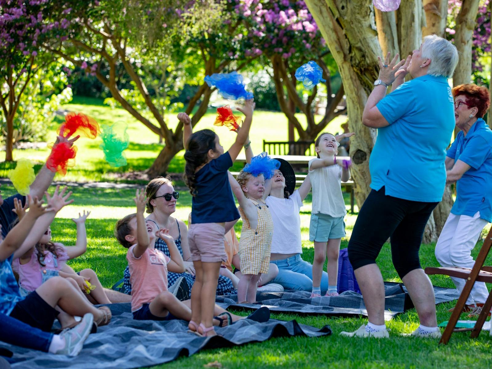 Kids and storytellers playing an activity with scarfs in the garden
