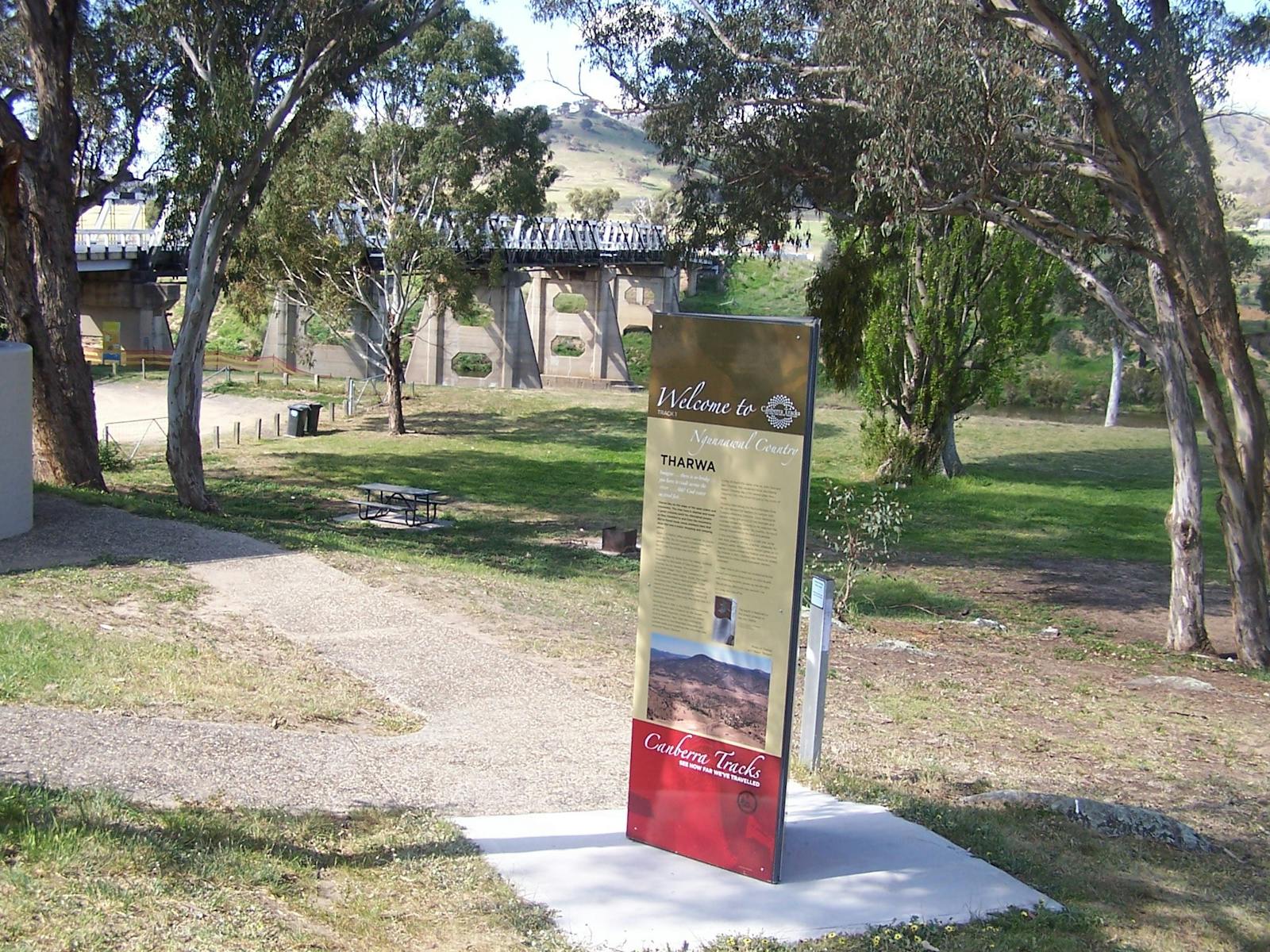 Tall information panel with park and bridge in background
