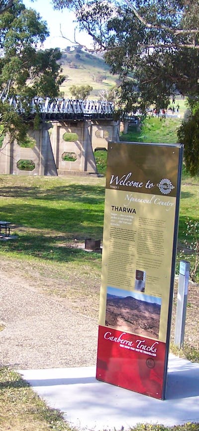 Tall information panel with park and bridge in background