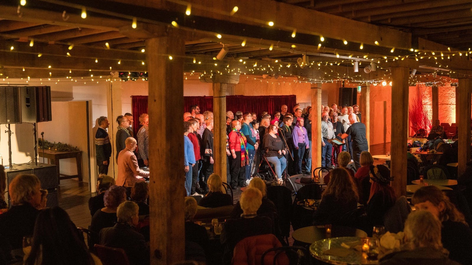 Choir performing under warm string lights at a cozy