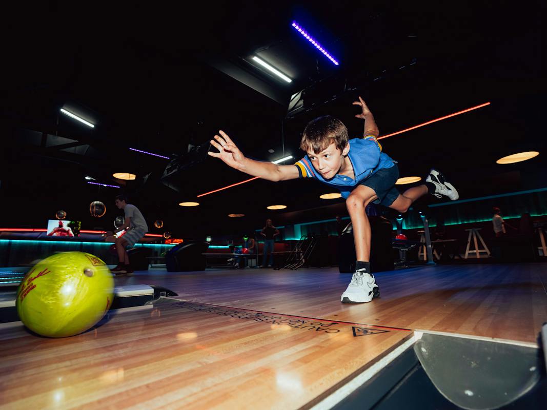 Young bowler in action releasing a yellow ball down the lane at ThunderBowl Alex Hills.
