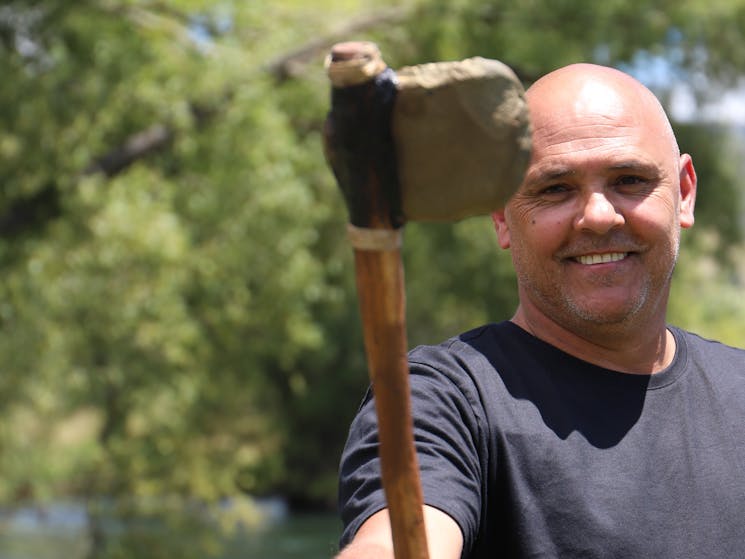 An Aboriginal man holding a newly made traditional stone axe