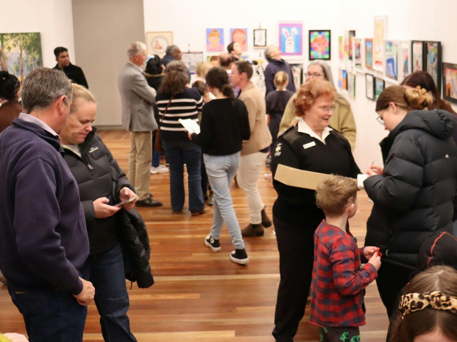 Artwork on wall and crowd at opening
